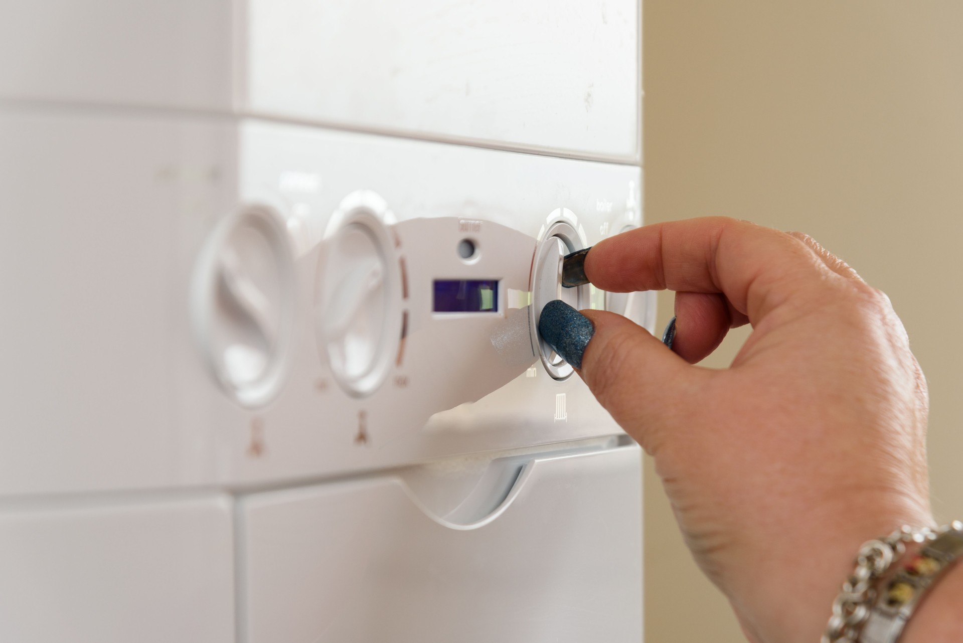 Woman with long nails turning the controls of a Gas Boiler