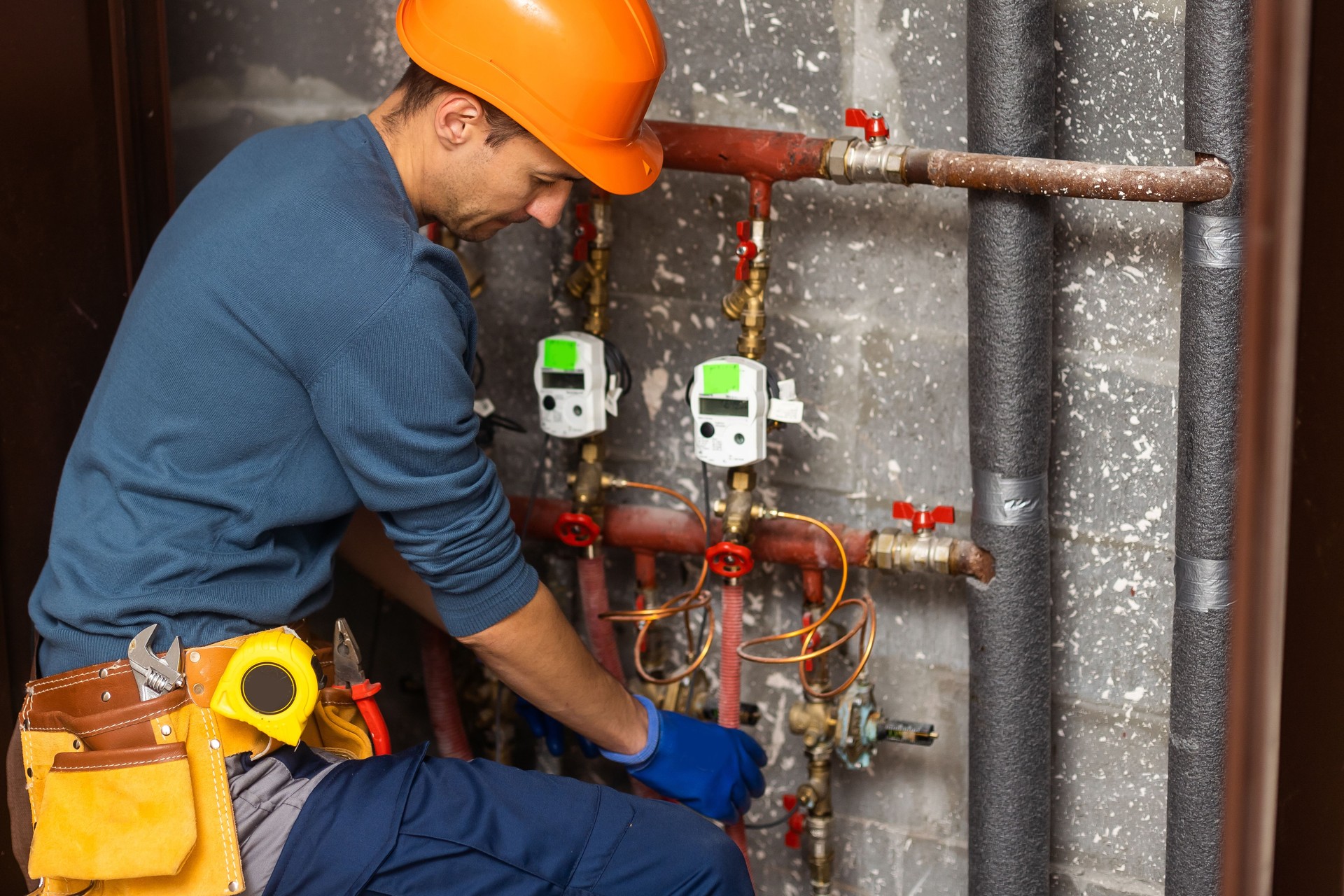 Maintenance engineer checking technical data of heating system equipment in a boiler room. Plumber installing pressure meter for house heating system