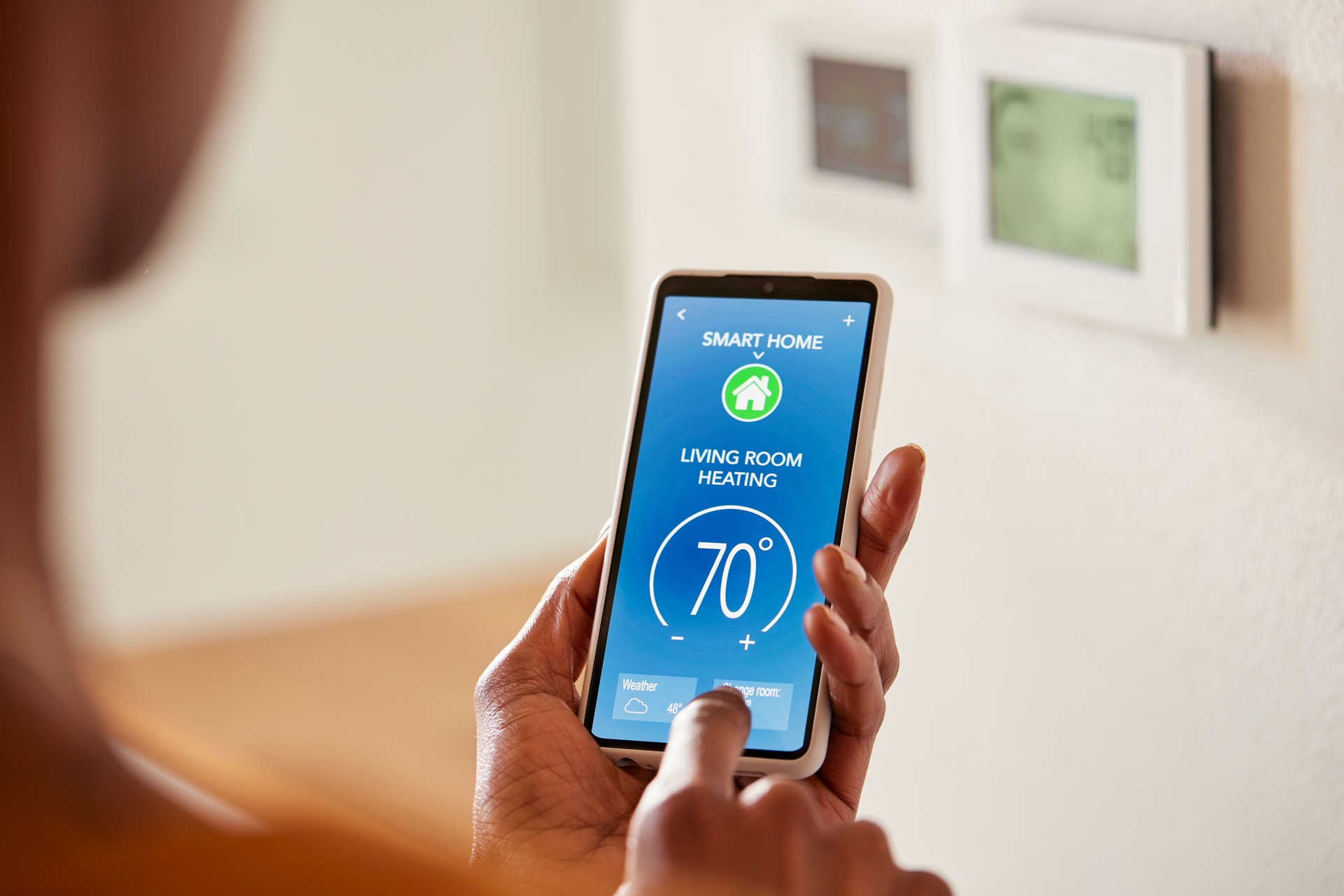 African american woman adjusting home temperature on mobile phone